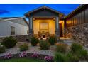 Inviting front porch with cozy seating and stone pillars, surrounded by lush landscaping and charming details at 22978 E Bailey Cir, Aurora, CO 80016