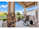 Relaxing front porch featuring stone pillars, comfortable seating, and a view of the well-maintained neighborhood at 22978 E Bailey Cir, Aurora, CO 80016