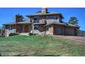 Stunning two-story home featuring stone accents, a balcony, two garage doors, and green lawn at 6300 Summer Star Ln, Golden, CO 80403