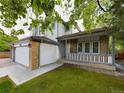 A house with a three-car garage and a cozy front porch, with a well-kept lawn and trees at 2720 E 121St Pl, Thornton, CO 80241