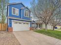 Blue two-story home with a white garage door and front lawn on a sunny day at 8793 Cloverleaf Cir, Parker, CO 80134