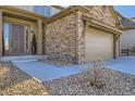 Close up of home's front entry and garage showing decorative stone exterior and drought resistant landscaping at 9559 Yucca Way, Arvada, CO 80007