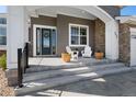 Inviting covered front porch with seating, stone accents, and manicured landscaping at 32 Latigo Pl, Littleton, CO 80123