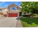 Attractive two-story house with a red garage door, tidy landscaping, and a healthy shade tree at 13235 Clermont Cir, Thornton, CO 80241