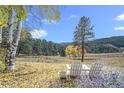 Picturesque backyard with Adirondack chairs and table beneath autumn trees at 20 W Ranch Trl, Morrison, CO 80465
