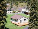 Charming home featuring a wooden deck, neutral siding, and a shingled roof, surrounded by lush greenery at 10049 S Turkey Creek Rd, Morrison, CO 80465