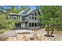Spacious backyard with a stone patio, fire pit, seating, and lush trees surrounding the property at 7317 Fremont Pl, Larkspur, CO 80118