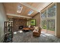 Cozy living room with stone fireplace, skylights, and walls of windows at 3251 Interlocken Dr, Evergreen, CO 80439