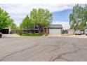 Two-story gray home featuring stone accents, manicured lawn, attached garage, and mature shade trees at 5861 S Orleans Way, Centennial, CO 80015
