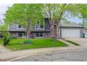 Charming gray two-story home boasting beautiful green lawn, an attached two-car garage, and mature shade trees at 5861 S Orleans Way, Centennial, CO 80015