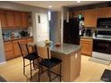 Kitchen featuring wood cabinets, an island with granite countertop, and stainless steel appliances at 5256 E 129Th Pl, Thornton, CO 80241