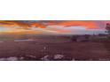 Scenic landscape at sunset, with open land, scattered trees, and mountains in the background under colorful cloud formations at 12925 Sierra Cir, Parker, CO 80138