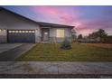New construction features stucco siding, stone accents, a dark gray garage door, and a small fir tree at 15 S Gray St, Lakewood, CO 80226