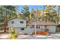 Charming exterior view featuring a two-story home with a red front porch surrounded by lush greenery at 31219 Florence Rd, Conifer, CO 80433