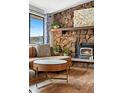 Cozy living room with a striking stone fireplace, wood floors, and view from a large window at 31219 Florence Rd, Conifer, CO 80433