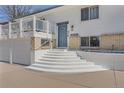 Welcoming front entrance with a stylish blue door, brick accents, and a grand set of white stairs at 4090 S Tamarac Dr, Denver, CO 80237