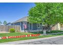 Quaint home featuring a cozy front porch, American flag, and a well-manicured lawn at 2791 Quarterland St, Strasburg, CO 80136