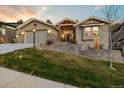 Inviting home boasts a well-manicured lawn, a two-car garage, and stone architectural detailing at 16113 Enchanted Peak Way, Monument, CO 80132