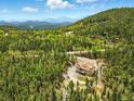 Aerial view of the charming home surrounded by dense forest and picturesque mountain scenery at 30041 Marys Dr, Conifer, CO 80433