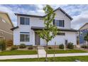 Inviting two-story home with white siding, black trim, a young tree, and well-manicured lawn at 10136 Worchester St, Commerce City, CO 80022