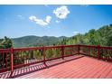 A red wooden deck features mountain views under a sunny sky, inviting relaxation and scenic appreciation at 32392 Lodgepole Dr, Evergreen, CO 80439
