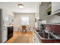 The kitchen has stainless steel sink, tiled backsplash, and white cabinets at 2345 S Williams St, Denver, CO 80210