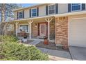 Inviting covered porch with white columns, brick accents, and landscaped garden at 1376 S Laredo Ct, Aurora, CO 80017
