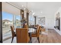 Bright dining area with modern chandelier, wood floors, neutral tones, and access to the balcony at 924 Andrews Crest Dr, Berthoud, CO 80513