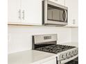 Close-up of stainless steel range and microwave with bright white cabinets and quartz countertops at 1935 Coolidge Way, Aurora, CO 80018