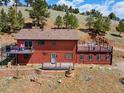 Exterior view of home with a deck, brick retaining wall, and grassy yard at 24170 Matterhorn Dr, Indian Hills, CO 80454