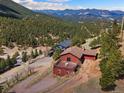 Aerial view of home with deck and mountain views nestled in a forest setting at 24170 Matterhorn Dr, Indian Hills, CO 80454