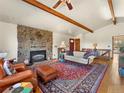 Inviting living room with stone fireplace, beamed ceiling, and hardwood floors at 24170 Matterhorn Dr, Indian Hills, CO 80454