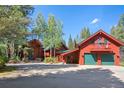 Red exterior of the home with green trim, complemented by mature trees and landscaping at 189 Ginger Quill Ln, Breckenridge, CO 80424