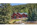 A picturesque exterior view of the red home nestled amongst lush greenery and a flowing river at 189 Ginger Quill Ln, Breckenridge, CO 80424