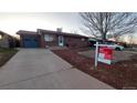 Charming brick home featuring a well-maintained lawn and professional real estate signage at 1977 S Yates S St, Denver, CO 80219