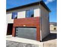 Side view of exterior of home with a gray garage door, wood paneling, modern windows, and number 103 above garage at 241 N Front St # 103, Monument, CO 80132
