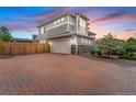 A large two car garage complemented by a brick driveway and beautiful flowering trees at 18056 E 104Th Way, Commerce City, CO 80022