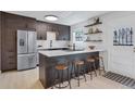 Modern kitchen featuring stainless steel appliances, a kitchen island with seating, and dark wood cabinetry at 9424 E Girard Ave, Denver, CO 80231