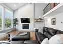 Bright living room featuring a stone fireplace, large windows, and comfortable leather seating area at 5441 S Dayton Ct, Greenwood Village, CO 80111