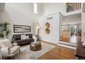 Sunlit living room boasts soaring ceilings and an open layout, complemented by hardwood floors at 4526 Lyndenwood Pt, Highlands Ranch, CO 80130