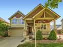 Inviting two-story home boasts a covered front porch with stone pillars and manicured landscaping at 301 Harvest St, Longmont, CO 80501