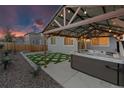 Backyard features a hot tub under a pergola strung with lights, complemented by artificial turf at 3844 Sandy Vista Ln, Castle Rock, CO 80104