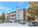 Apartment building featuring updated exterior with brick accents, private balconies, and landscaped grounds in winter at 14208 E 1St Dr # C1, Aurora, CO 80011