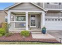 Inviting front porch with white railings, a bench, a decorative pot, and a welcoming entryway to this charming home at 9879 Sydney Ln, Highlands Ranch, CO 80130