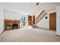 Spacious living room with a brick fireplace, a staircase, and neutral carpet at 2883 W Long Cir # E, Littleton, CO 80120
