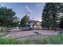 The back of the home features a sand box, hot tub and yard with trees on a large lot at 5080 Barn Swallow Way, Parker, CO 80134