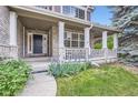 Inviting covered porch with white columns, brick accents, and a beautifully landscaped garden at 2215 Parkview Dr, Longmont, CO 80504