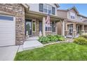 Inviting front porch with stone accents, green door, an American flag, and lush landscaping at 853 Jenny Ln, Berthoud, CO 80513