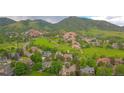 An aerial view shows a home located in a neighborhood next to a golf course and large mountains at 5569 Willow Springs Dr, Morrison, CO 80465