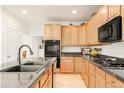 Well-lit kitchen features light wood cabinetry, stainless steel appliances, and granite countertops at 13664 Cherry St, Thornton, CO 80602